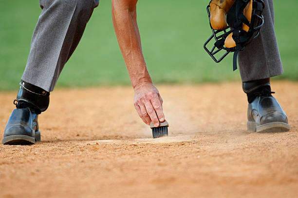 Close up detail of the hand of a baseball umpire as they clean off home plate between batters.